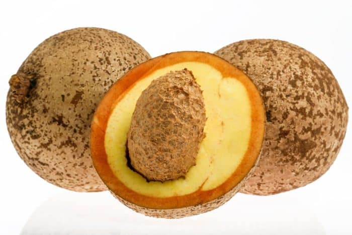 whole and half mamey apple placed on a white isolated background