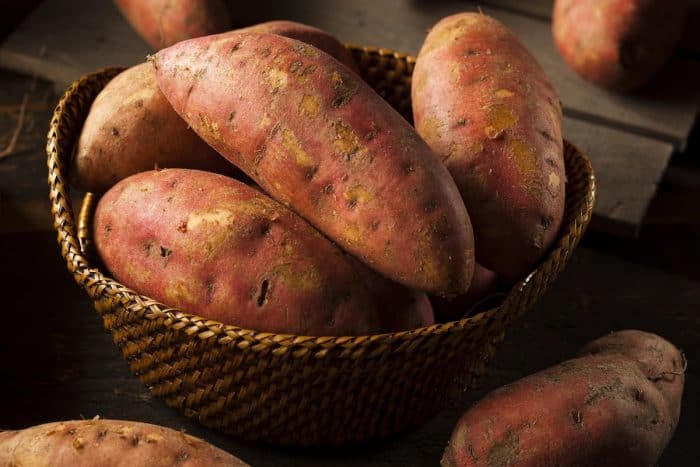 Organic Raw Sweet Potatoes on a wooven basket