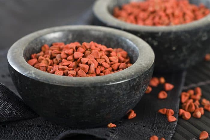 a bowl full of Annatto seeds placed on a kitchen counter top