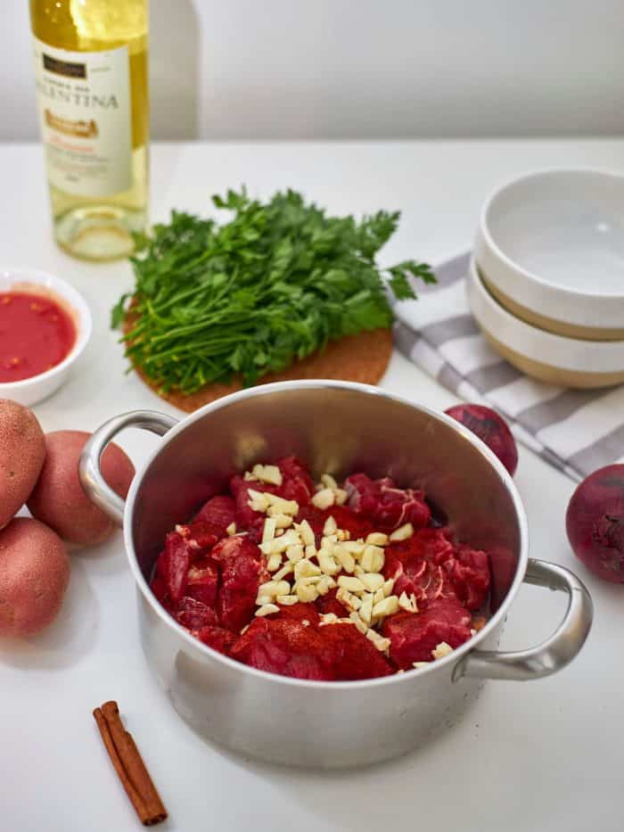 In a large mixing bowl, combine the beef, half the garlic, paprika, olive oil, salt, and pepper to taste.