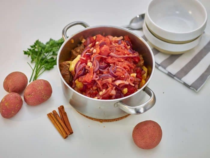 Pour in beef broth and add a cinnamon stick, then stir to combine.