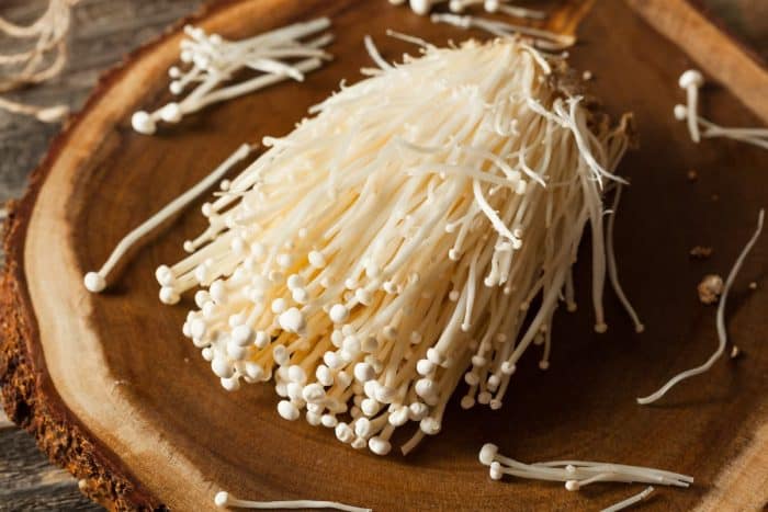 Raw Organic Enoki Mushrooms on a wooden board