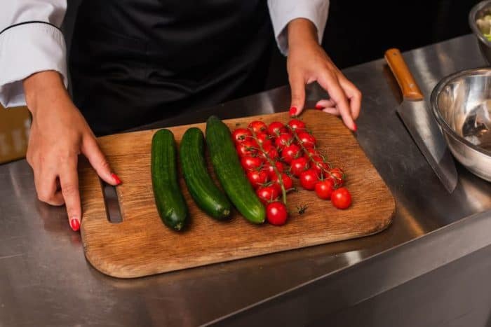 Cropped view of african american woman near ripe vegetables on cutting board