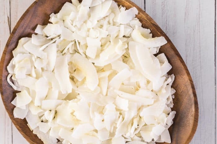 a wooden bowl full of Dehydrated coconut flakes
