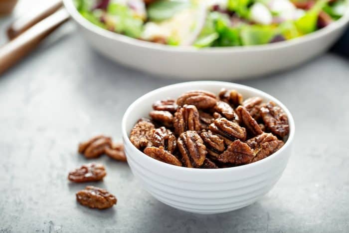 a small white bowl full of candied pecans