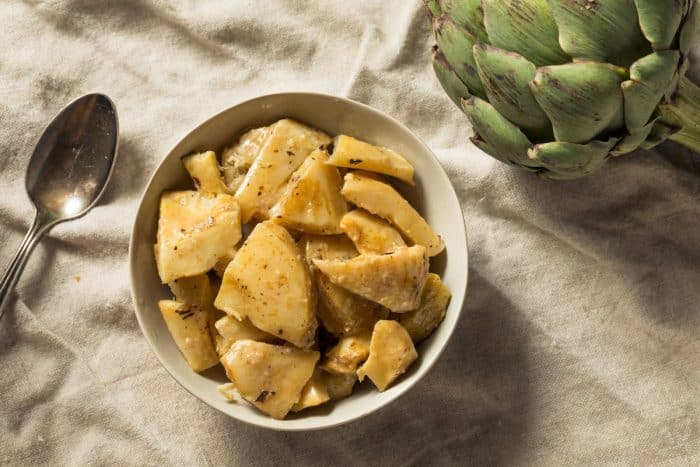 a white bowl full of Organic Marinated Artichoke Hearts