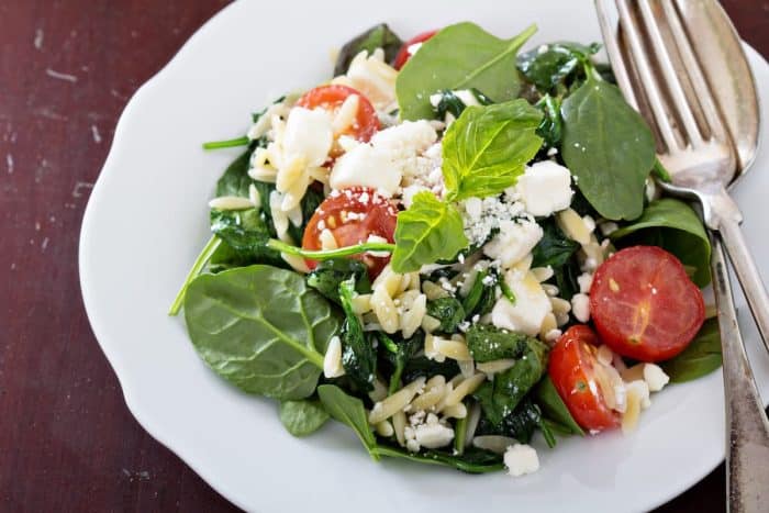 a plate of Pasta salad with orzo, spinach and feta with spoon and fork