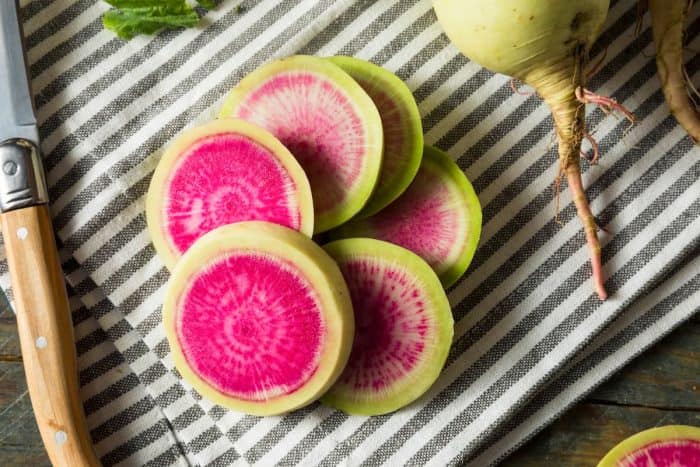 Raw Green and Red Organic Watermelon Radishes placed on a kitchen table