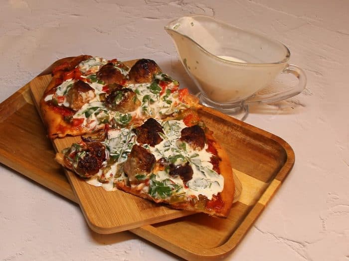 Remove the pizza from the oven and divide into 8 slices. Drizzle the garlic sauce over the top and serve!