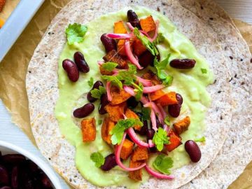 Packed with the natural sweetness of roasted sweet potatoes, the heartiness of red kidney beans, the tang of quick-pickled red onions, and a creamy avocado sauce, each taco is a feast for the senses. 