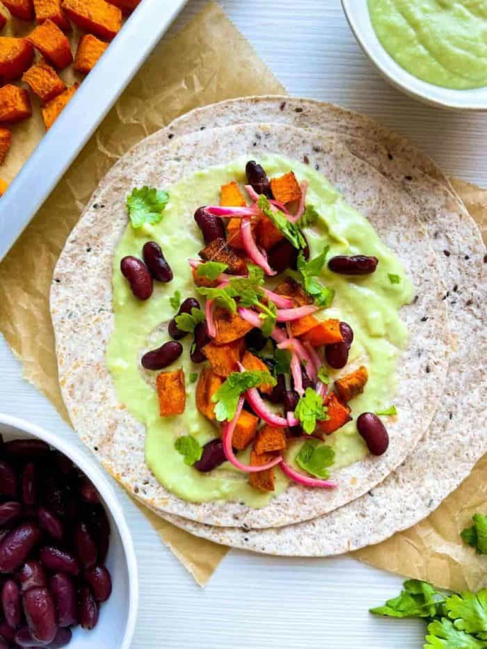 Packed with the natural sweetness of roasted sweet potatoes, the heartiness of red kidney beans, the tang of quick-pickled red onions, and a creamy avocado sauce, each taco is a feast for the senses. 