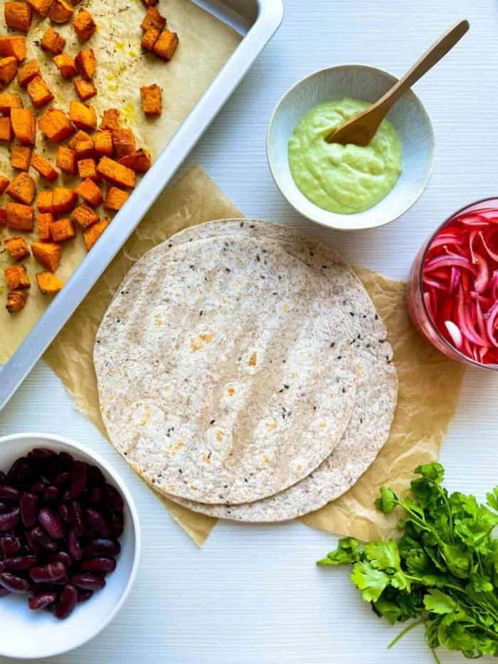 ingredients for sweet potato tacos placed on a white table countertop
