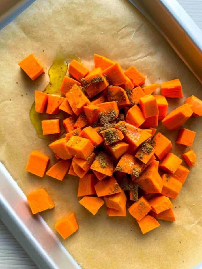 In a large bowl, toss the sweet potatoes with ground cumin and olive oil. Season with salt and pepper to taste. 