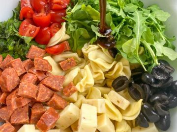 Pour half of the balsamic vinaigrette over the salad ingredients and gently fold everything together with a spoon or salad tongs, ensuring that the tortellini and add-ins are evenly coated with the dressing.