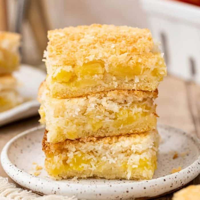 A vegan dessert that's bursting with bright flavors, each pineapple coconut square offers a sweet pineapple layer nestled between a crumbly coconut base and a golden, toasty topping.