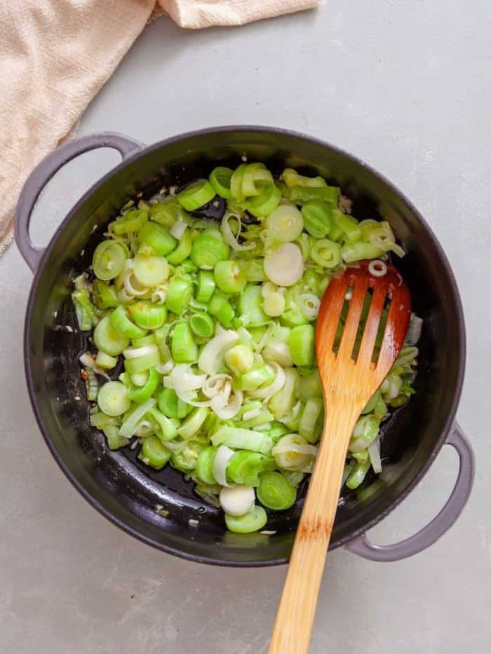 In a large, high-sided skillet over medium heat, sauté garlic and leeks in butter and olive oil until tender
