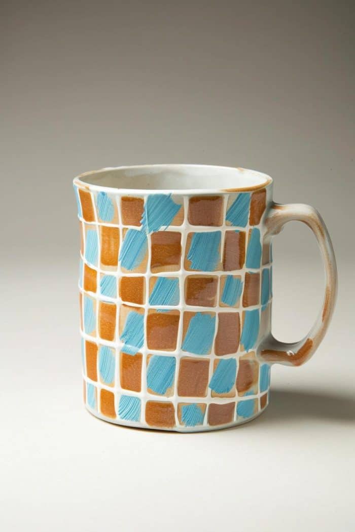 Lovely and country-inspired, the check pattern on this mug is painted in brown and blue and outlined with white paint to create a distinctive look.