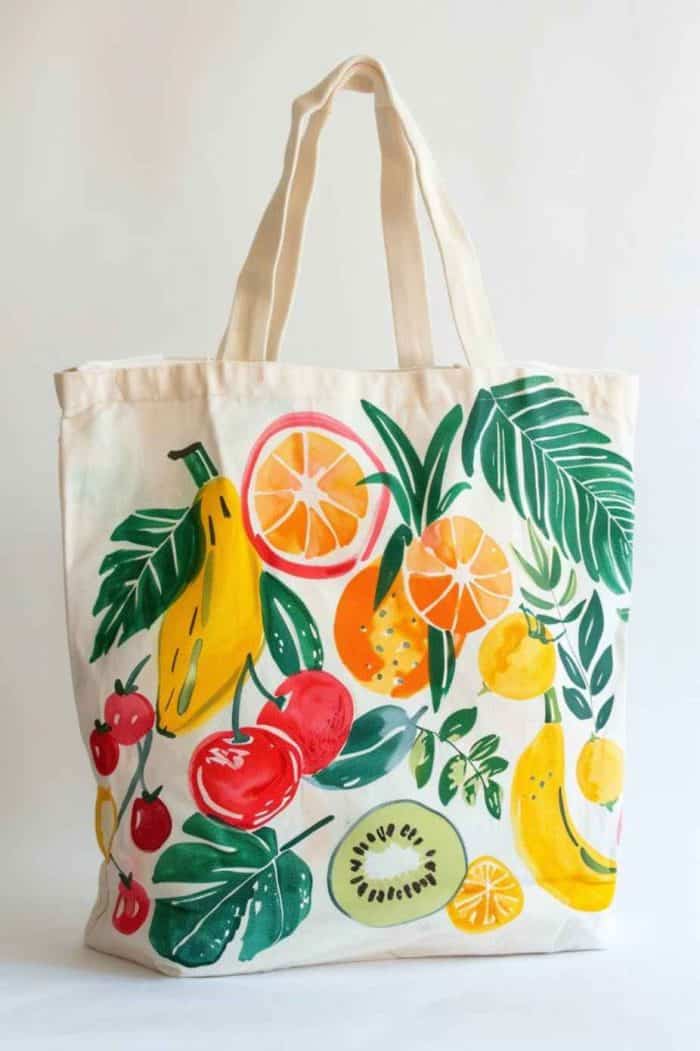 Vividly colored fruits, from sun-kissed oranges to deep red cherries to bright green kiwis, spill across the tote's surface in a bountiful display.