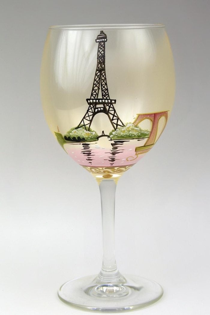 This glass features classic Parisian elements such as the Eiffel Tower, a beret, or a fleur-de-lis, set against a soft pastel background reminiscent of a Parisian cafe. 