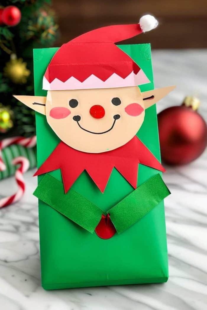 This elf craft is easily identifiable by his pointed ears, cut from paper and attached to the sides of the bag. And with his red Christmas hat, he’s the perfect addition to your DIY holiday decor ensemble!