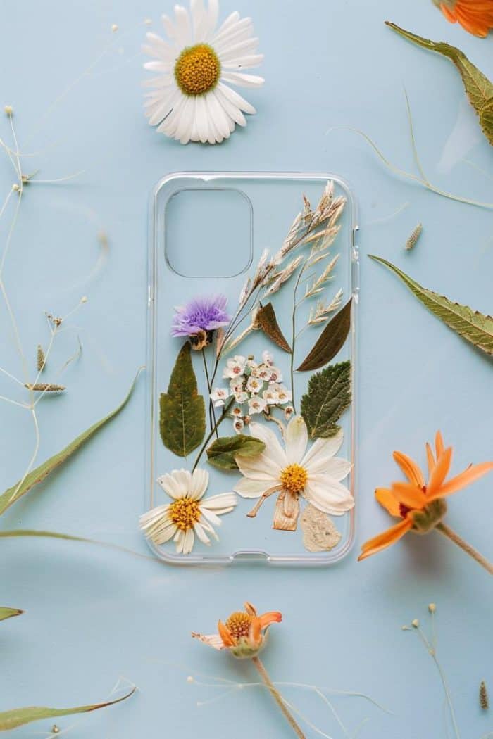 Transform a clear phone case by arranging pressed flowers onto the back, sealing them in place for a custom design.
