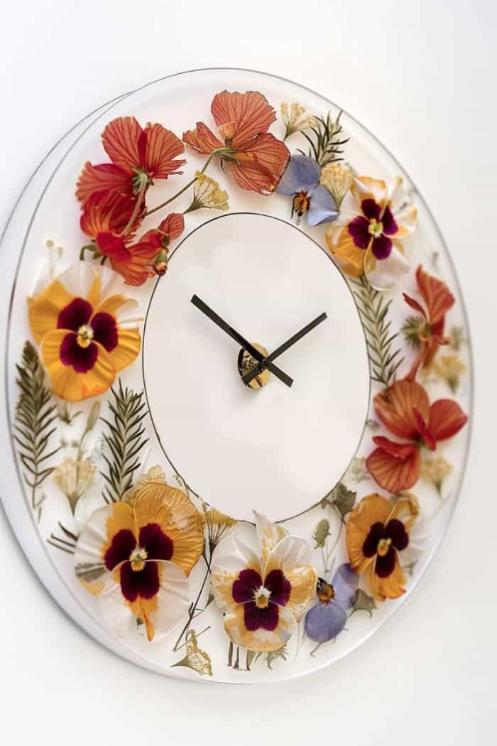 Assemble wall clocks by placing pressed flowers on the clock face before sealing them with a clear layer.