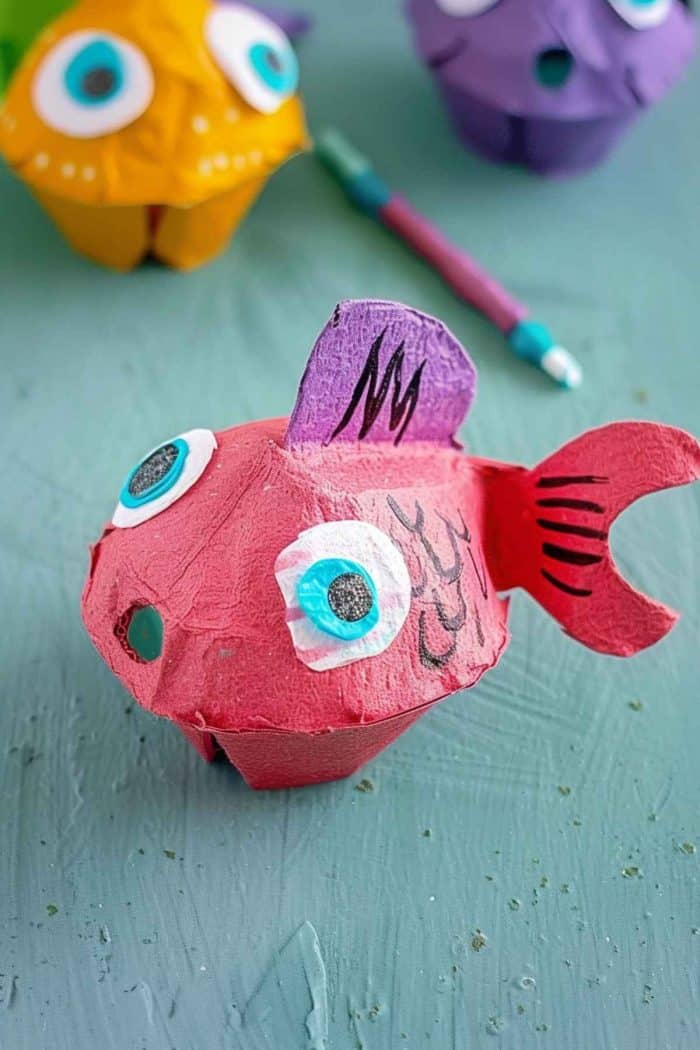 Use egg carton cups as the foundation for a colorful fish craft, with its body, fin, and tail cut from cardboard painted in bright hues. Draw scales and add details like eyes for a realistic appearance. 