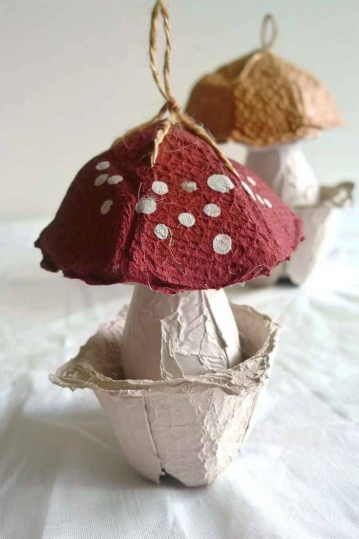 Use egg carton cups as bases for cardboard mushrooms, painting them earthy tones with white polka dots for a classic look. 