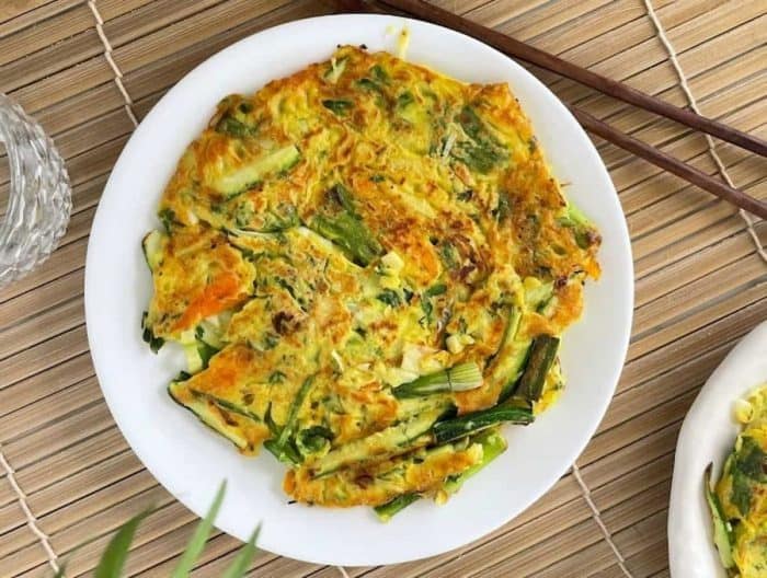 This dish has a variety of fresh vegetables like zucchini, carrots, and cabbage mixed with flour, eggs, and flavorful seasonings before being pan-fried to golden perfection.