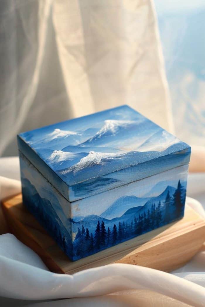 Paint a serene mountain landscape with broad strokes of white and blue to create snow-capped peaks against the sky and precise strokes of black to create trees. 