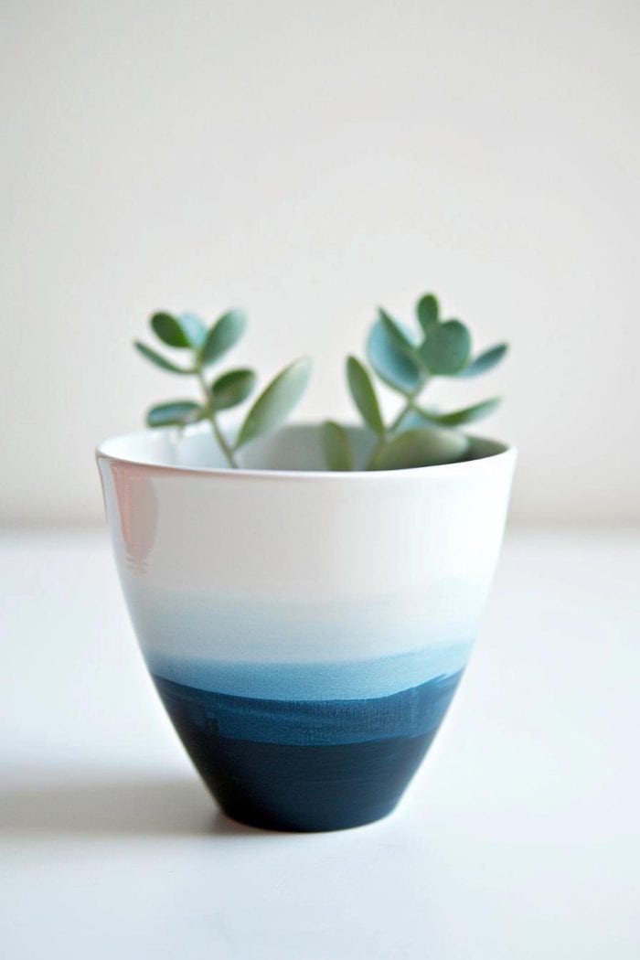 The lower half of the vase is immersed in a deep indigo paint, creating a sharp contrast with the untouched white porcelain above. 