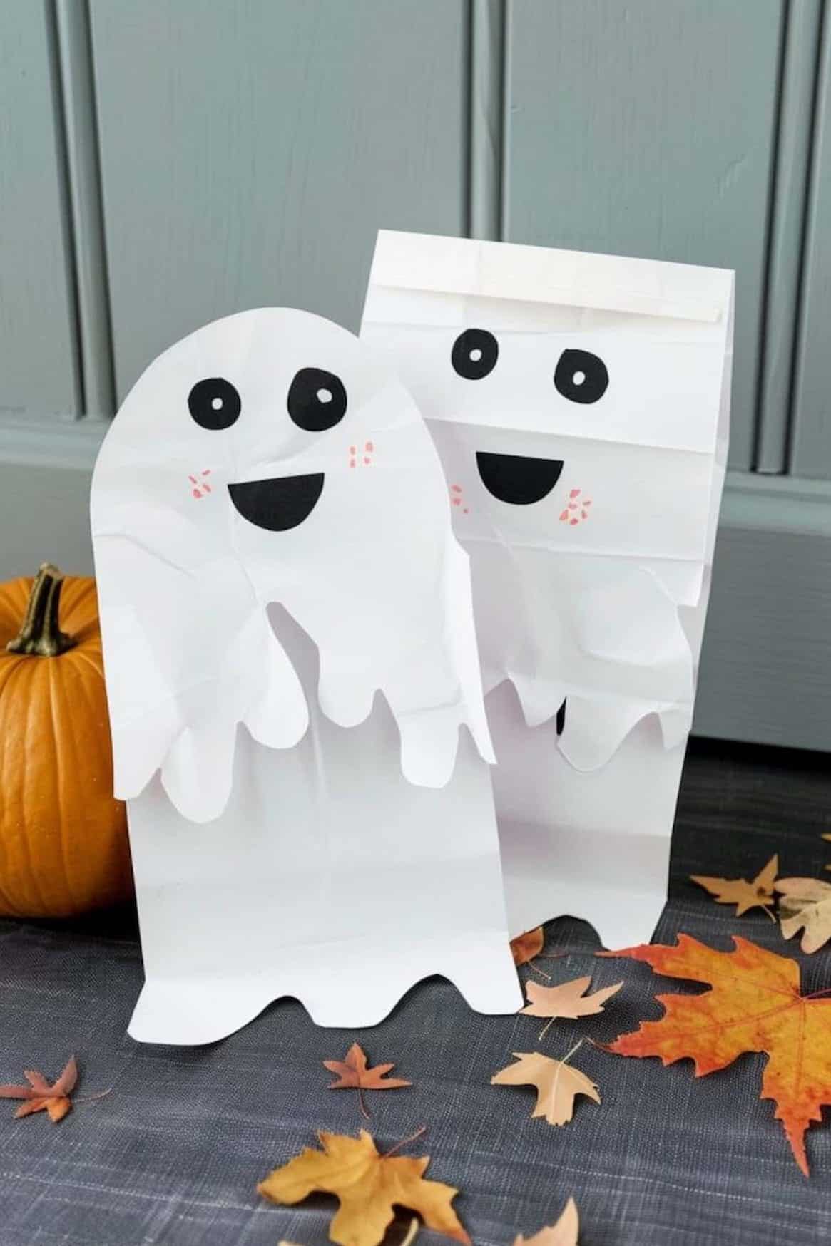 Cut out a pair of eyes and a mouth from black paper to create friendly and adorable ghost faces on white paper bags, then decorate their cheeks with pink freckles.