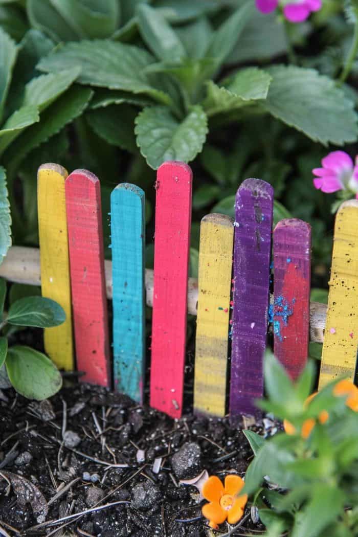 Make a playful fairy garden fence with popsicle sticks. Paint the sticks in bright colors and build the fence to protect the tiny magical world.