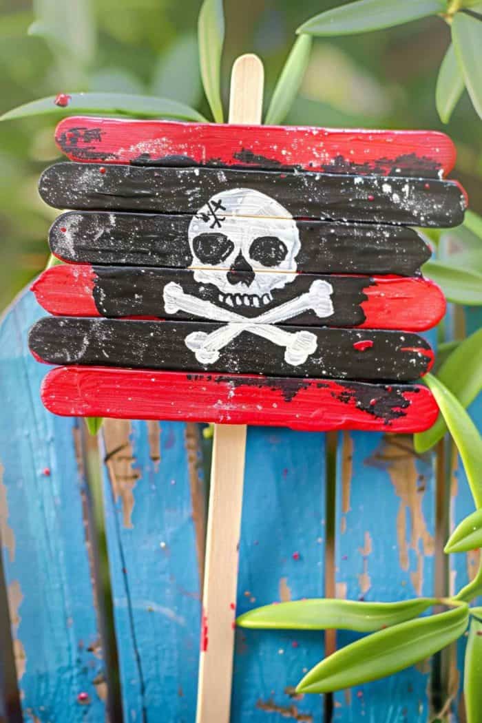 Construct a pirate’s flag using popsicle sticks. Glue four sticks together to form a rectangular shape, paint them red and black, then attach them to a popsicle stick that acts as the “pole.” Paint a white skull on the flag to complete the look.