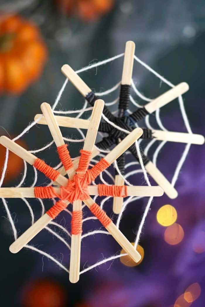 Craft intricate spider webs using popsicle sticks and yarn. Glue three sticks together in a star shape, then weave yarn around the sticks to form a web pattern. 