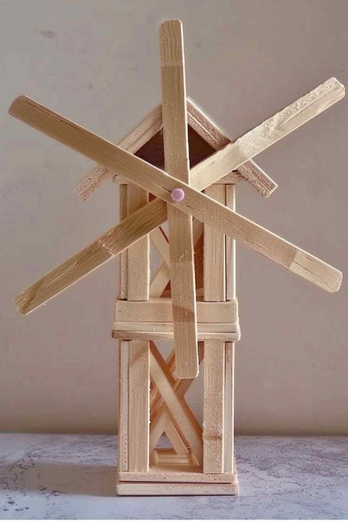 Create a playful windmill using popsicle sticks. Construct the base by gluing sticks into square or rectangular shapes. 