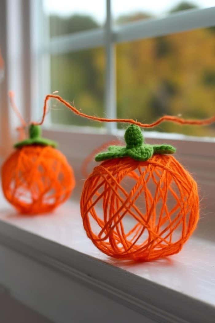 Create a garland with small pumpkins made by wrapping yarn around a balloon, applying glue, and then popping the balloon once the glue dries to leave a hollow yarn pumpkin.