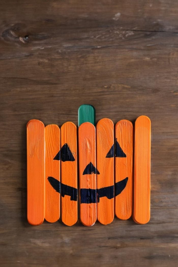 Form a pumpkin shape by lining up popsicle sticks side by side and painting them orange.