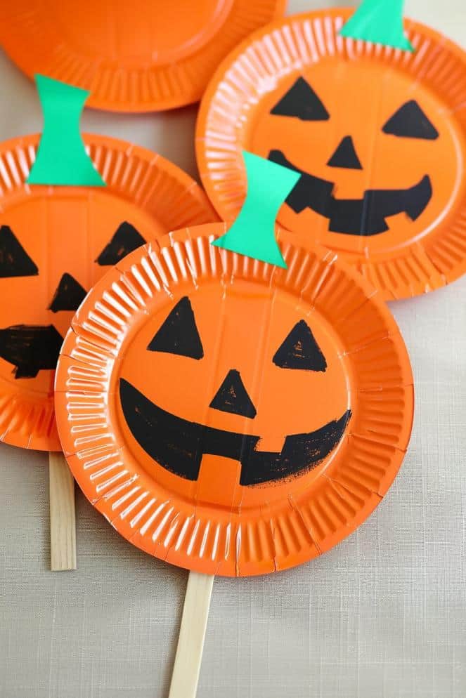 Cut paper plates into pumpkin shapes and paint them orange with green stems.