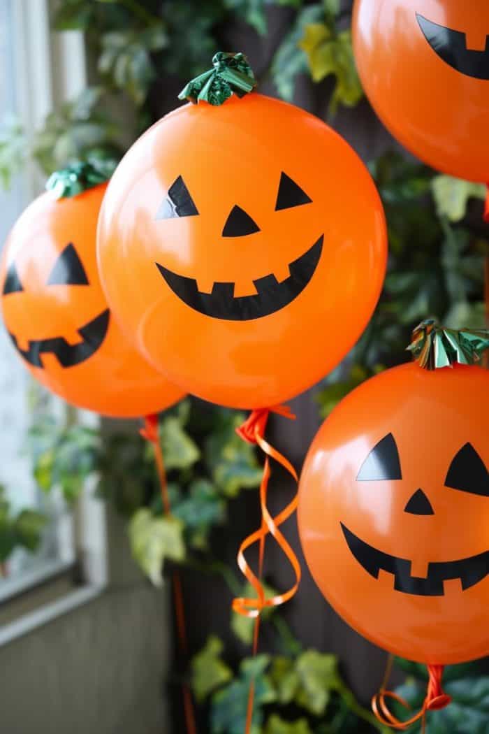 Create balloon characters by inflating orange balloons and using markers or adhesive black craft paper to add pumpkin faces.