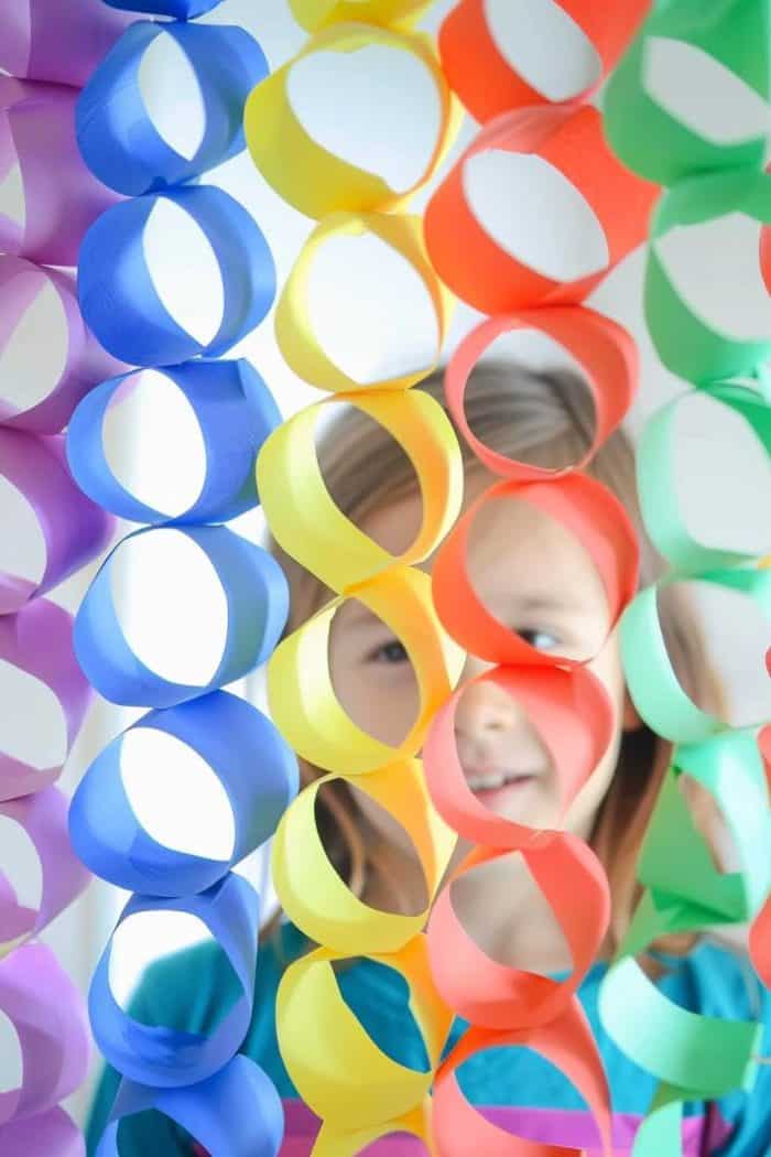 Cut strips of paper in graduated shades of the rainbow and loop them into interlocking circles, securing each with pins, tape, or glue. 