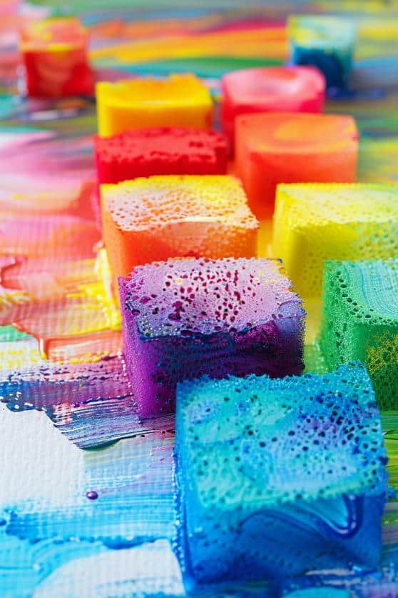 Dip sponges into various colored paints and press them onto paper to create a vibrant, textured rainbow effect. 
