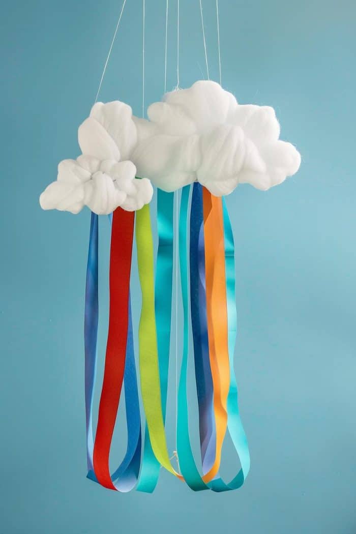 Assemble a mobile by gluing fluffy cotton balls together, and hang strips of colored ribbon or paper below to represent rainbows. 