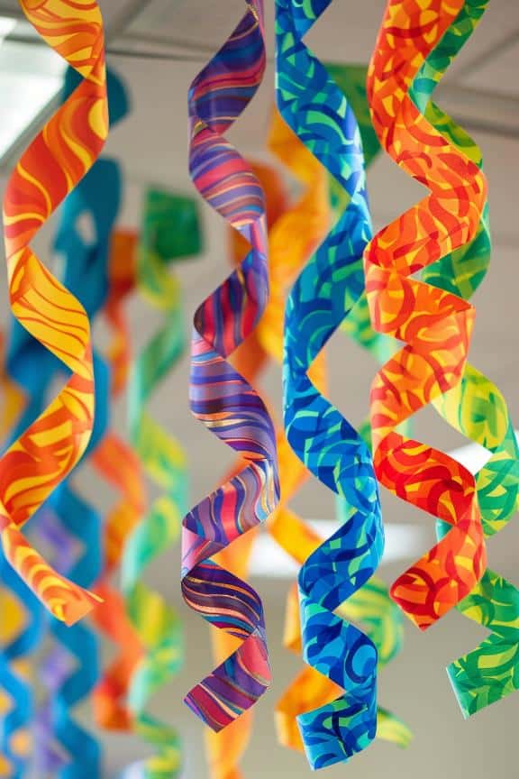 Cut colored paper with swirly patterns into long spirals to resemble the scaly skin of a snake. 