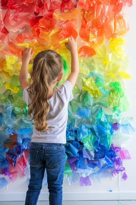 Adhere clear contact paper to a wall, sticky side out, and provide children with pre-cut pieces of cellophane paper or used plastic bags in rainbow colors to stick onto the contact paper, creating a large-scale mural. 