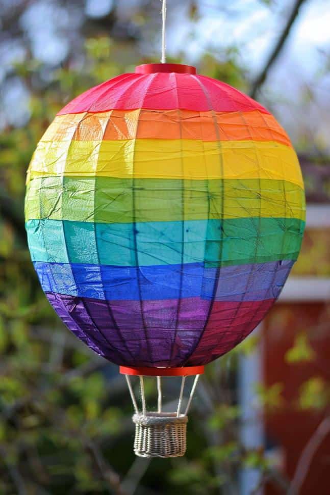 Construct a 3D hot air balloon by covering a paper lantern with overlapping strips of translucent colored paper, creating a rainbow effect. 