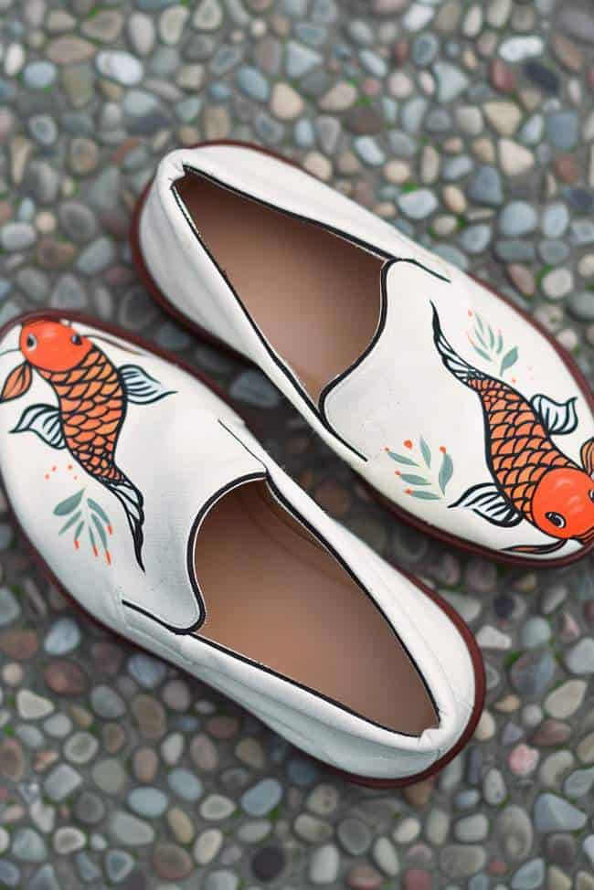 Slip-ons are adorned with orange and white koi fish gliding through the surface.