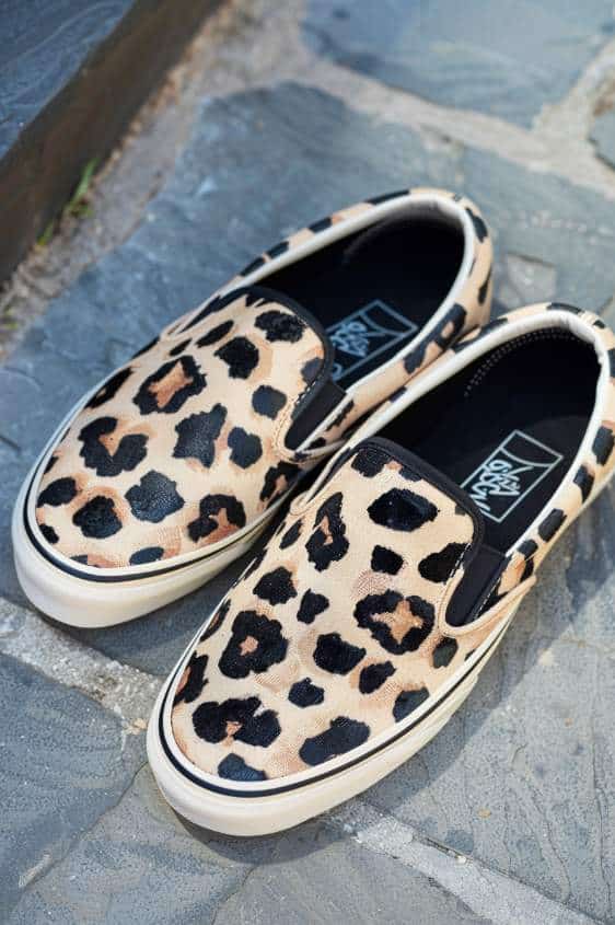 These slip-ons prowl with a leopard spot pattern, featuring hand-painted brown and black spots scattered across a beige base. 