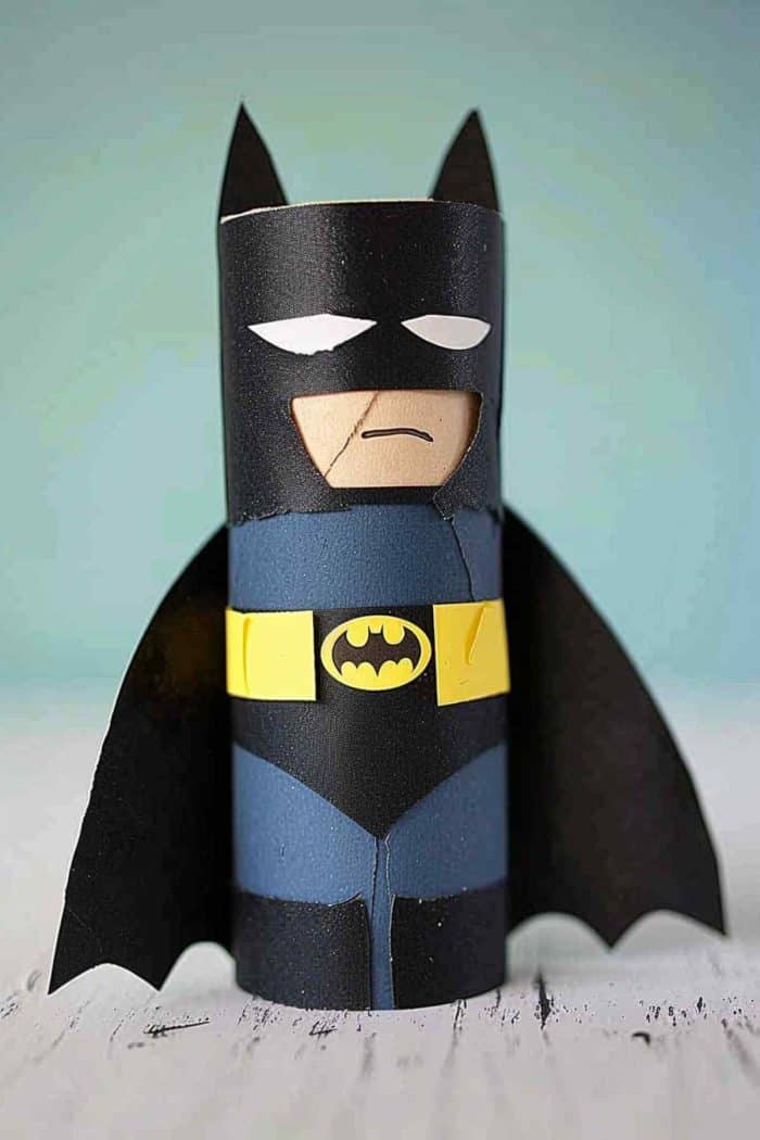 To create Batman, paint a toilet paper roll deep gray and add the classic costume with painted black toilet paper and the emblem cut from yellow paper! For his cape, use a piece of black fabric or paper glued to the back.