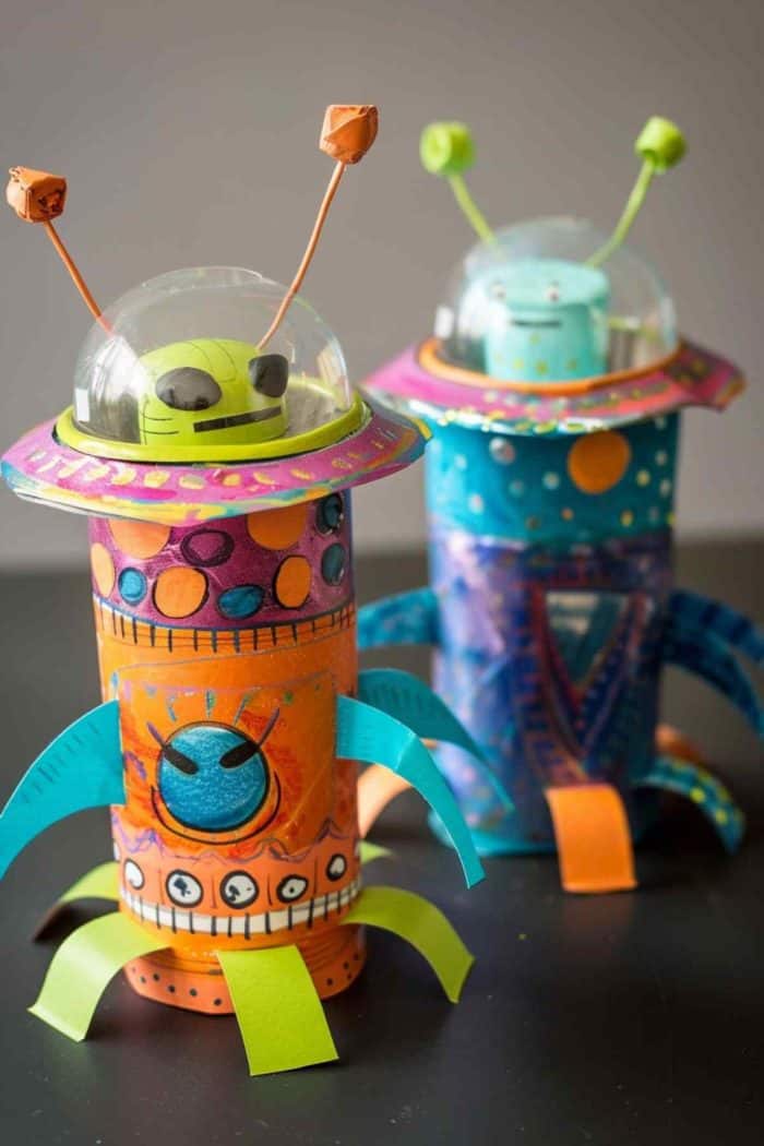 Fashion alien spaceships using toilet paper rolls for the base, painting them in metallic or bright colors. Attach a clear plastic cup on top for the dome, and if desired, place a small alien figure inside. 